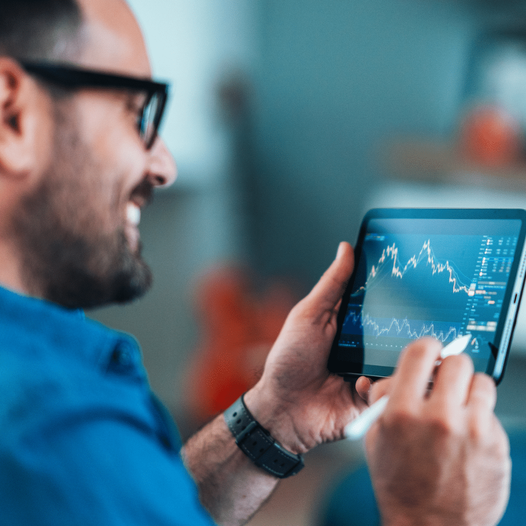 smiling man with tablet viewing market data analysis